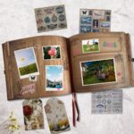A vintage-style scrapbook journal with a 3D embossed cover, retro lock, and map details, open to show colorful pages.