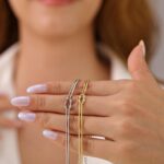 Close-up of a GRCLD gold and silver stainless steel love knot braided chain bracelet with a lobster claw clasp.