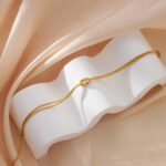 Close-up of a GRCLD gold and silver stainless steel love knot braided chain bracelet with a lobster claw clasp.