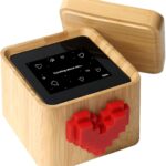 A black and white Lovebox device with a spinning red pixel heart on top, displaying a message on its screen.