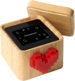 A black and white Lovebox device with a spinning red pixel heart on top, displaying a message on its screen.