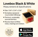 A black and white Lovebox device with a spinning red pixel heart on top, displaying a message on its screen.