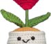 A small, red crochet doll with a flower head and a heart-shaped body, resting on a flat surface.