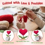 A small, red crochet doll with a flower head and a heart-shaped body, resting on a flat surface.
